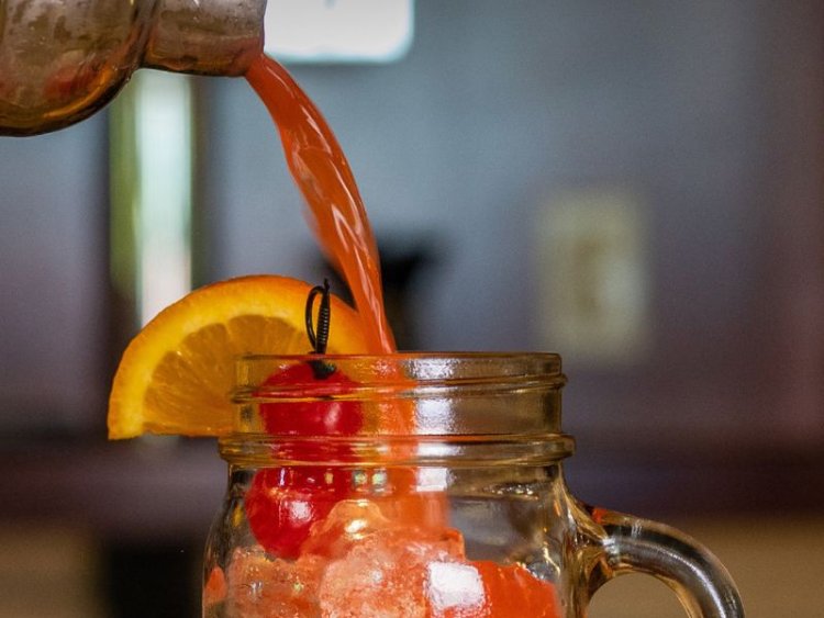 Old fashioned being poured into a mason jar mug.