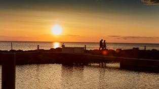 A couple standing in front of Sister Bay during a sunset