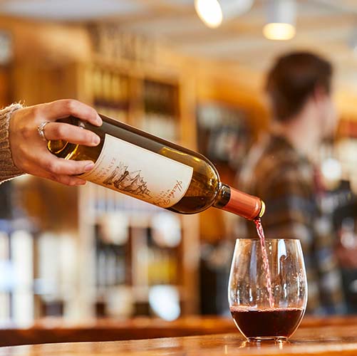 A person pouring a bottle of wine into a glass.