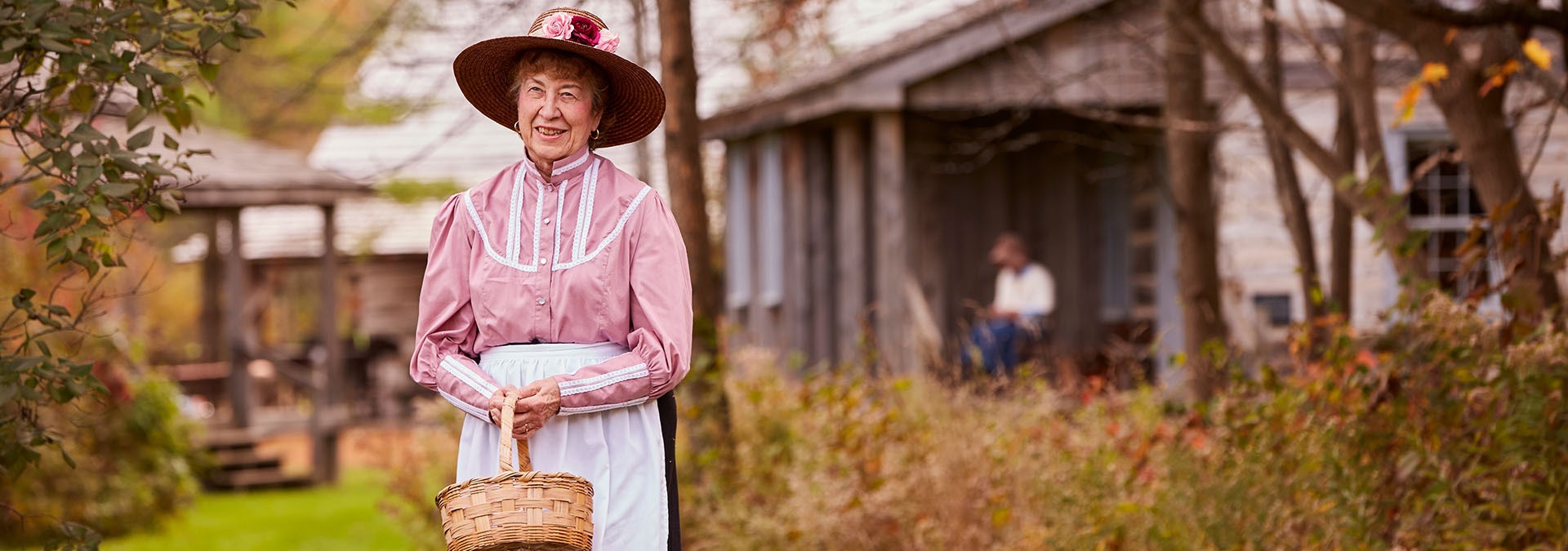 Woman in a historical costume holding a basket.