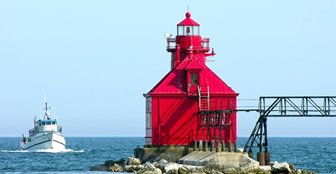 Lighthouse on a rocky point with a boat coming in.