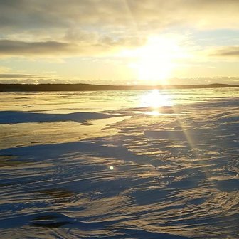 The sun rising over the snowy lake.