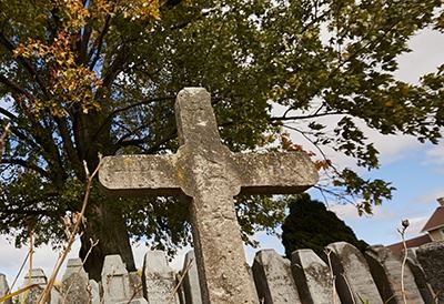 A stone cross in front of a tree.